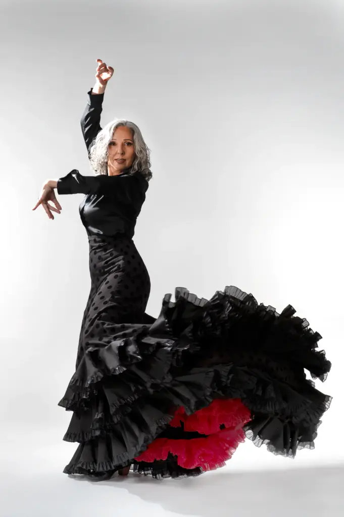 Rocío Pozo bailando con bata de cola negra de volantes rojos y los brazos en alto